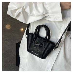 Dettaglio mini borsa nera a grana con chiusura argento su una camicia bianca