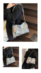 Detail of silver tote bag with chain strap, leather texture and plush bear pendant