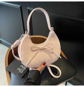 Vue détaillée du sac demi-lune rose pâle en suédine avec nœud décoratif élégant