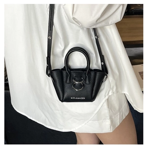 Dettaglio micro borsa in pelle martellata nera con anelli metallici e tracolla