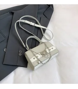 Détail du sac bandoulière tissé beige avec boucle coeur argentée et ornements de chaîne