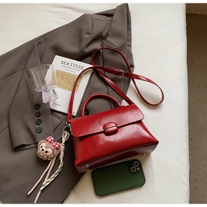 Détail d'un sac bandoulière en cuir rouge avec boucle et accessoire de charme ours mignon