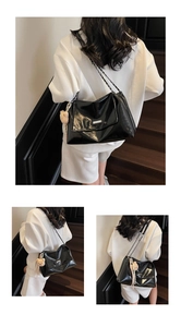 Detail of black glossy tote bag with chain strap and cute plush bear charm on model
