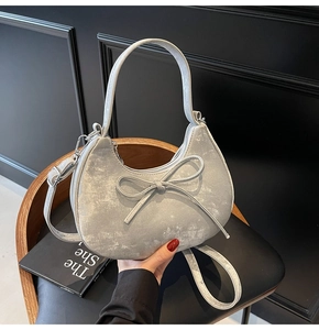 Détail du sac croissant argenté avec nœud et texture métallique sur une chaise vintage