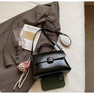 Vue détaillée du mini sac noir en similicuir avec porte-clés singe et bandoulière