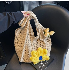 Detail of hollow woven tote bag featuring a large yellow crochet flower and blue core