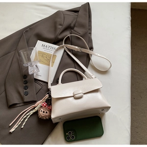 Détail d'un sac bandoulière beige crème avec charm singe et un livre d'art de Matisse