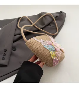 Detail der gewebten Strohtasche mit rosa Spitzenblumen und Perlenverzierungen