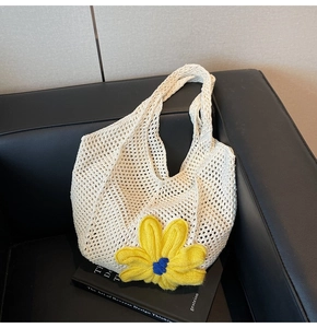 Macro detail of a white crochet tote bag featuring a vibrant yellow knitted flower accent