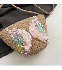 Detail der handgewebten Strohtasche mit bunten 3D-Spitzenschmetterlingen und Perlen