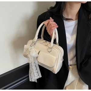Detail of creamy white Boston bag with lace bow and pearl pendant accessory