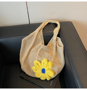 Detail of beige crochet tote bag featuring a large yellow sunflower knit decoration