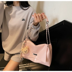 Close-up of pink glossy tote bag with silver chain strap and plush bear charm