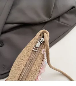Detail einer handgewebten Stroh-Beuteltasche mit Metallreißverschluss und Blumendekor