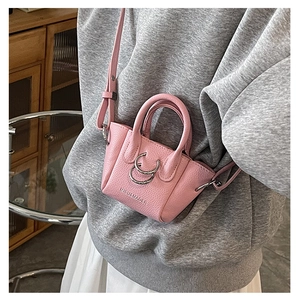 Dettaglio di una micro borsa rosa per rossetto in pelle martellata con fibbia argentata