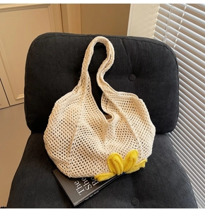 Detailed close-up of hollow crochet tote bag with a 3D yellow floral accent on soft fabric