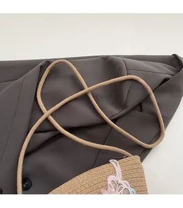 Detailansicht der Stroh-Eimertasche mit 3D-Blumen- und Schmetterlingsstickerei