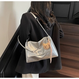 Silver metallic tote bag with chain strap and cute bear charm shown on black blazer