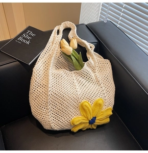 Detail of white hollow crochet tote bag featuring a large 3D yellow knitted flower decoration