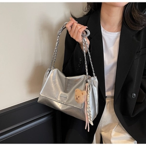Detail of silver metallic tote bag with chain strap and cute bear keychain accessory