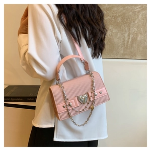 Détail du sac bandoulière rose en PU tressé avec boucle cœur en métal et chaîne argentée