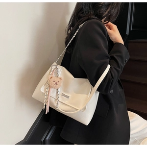 Detail of off-white patent leather shoulder bag with gold chain and teddy bear charm