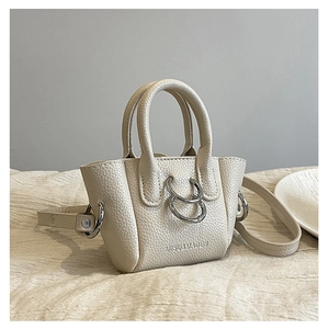 Dettaglio della borsa in pelle martellata beige con anelli metallici e logo del marchio