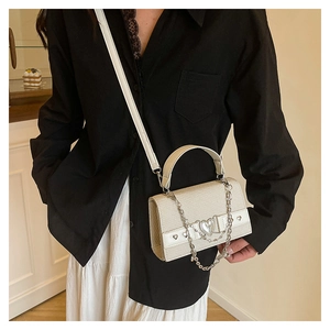 Petit sac à bandoulière crème élégant avec boucle cœur sur un mannequin féminin