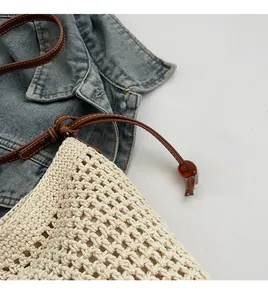 Detail of beige crochet woven tote bag featuring leather straps and decorative wooden beads