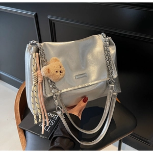 Detailed macro view of metallic silver tote bag texture with chain and plush bear charm