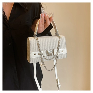Détail du sac à bandoulière crème avec texture tissée et boucle en métal en cœur