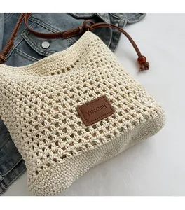 Detail of handwoven cream tote bag with dark brown leather straps and embossed logo tag