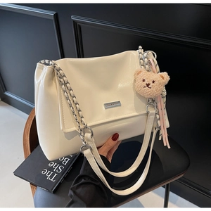 Detail of off-white PU leather tote bag with metal chain strap and cute bear charm