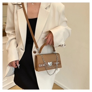 Détails d'un sac carré marron tissé avec boucle coeur argentée et éléments de chaîne