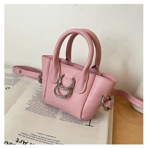 Dettaglio ravvicinato di una mini borsa rosa in pelle grana litchi su una rivista