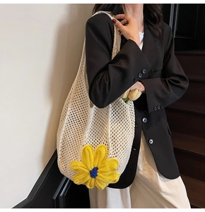Detail of beige crochet tote bag with yellow knit flower worn on a black casual blazer
