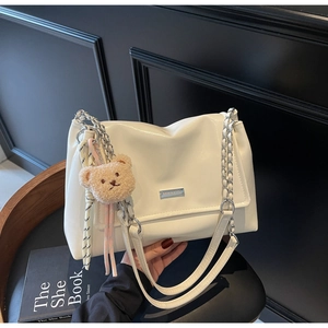 Detailed close-up of white soft leather tote bag with metal chain strap and logo