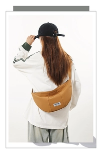 Détail du sac demi-lune en nylon kaki avec étiquette tissée et fermeture éclair noire