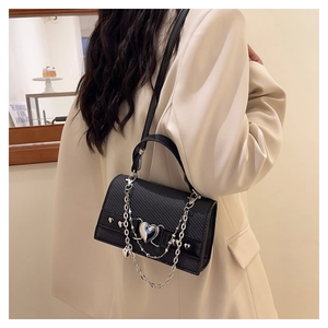 Détail du sac bandoulière noir à texture carbone et breloque chaîne cœur argentée
