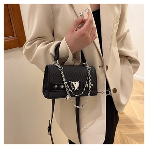 Détail du sac noir avec boucle en forme de cœur argentée et chaînes multicouches