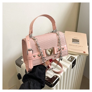 Détail du sac rose en tissu à chevrons avec chaîne argentée et fermoir en cœur