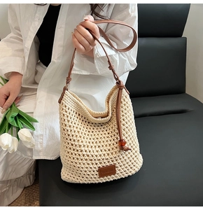 Detail of hand-woven mesh tote with brown leather trim and red bead accent