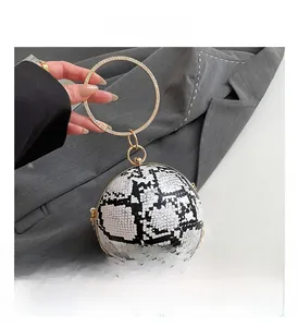 Detailed close-up of spherical snakeskin bag with diamond-encrusted gold ring handle