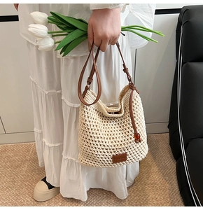 Detail of cream woven tote bag featuring brown leather straps and brand logo patch
