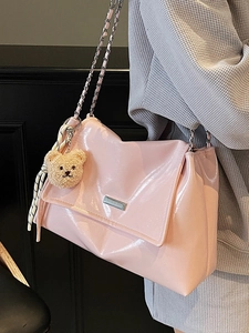 Pink glossy faux leather tote bag with chain strap and cute bear charm worn by a model