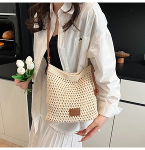 Detail of beige crochet tote bag with brown leather strap and decorative wood bead buckle