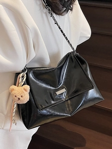 Minimalist black patent leather tote bag with metal chain strap and plush bear charm