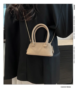 Detail of beige lychee texture mini crossbody bag with golden bead chain and double handles