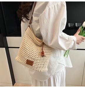 Detail of hand-woven off-white tote bag with brown leather strap and logo patch