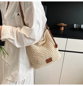 Detail of hand-woven tote bag showing beige mesh texture and brown leather strap
